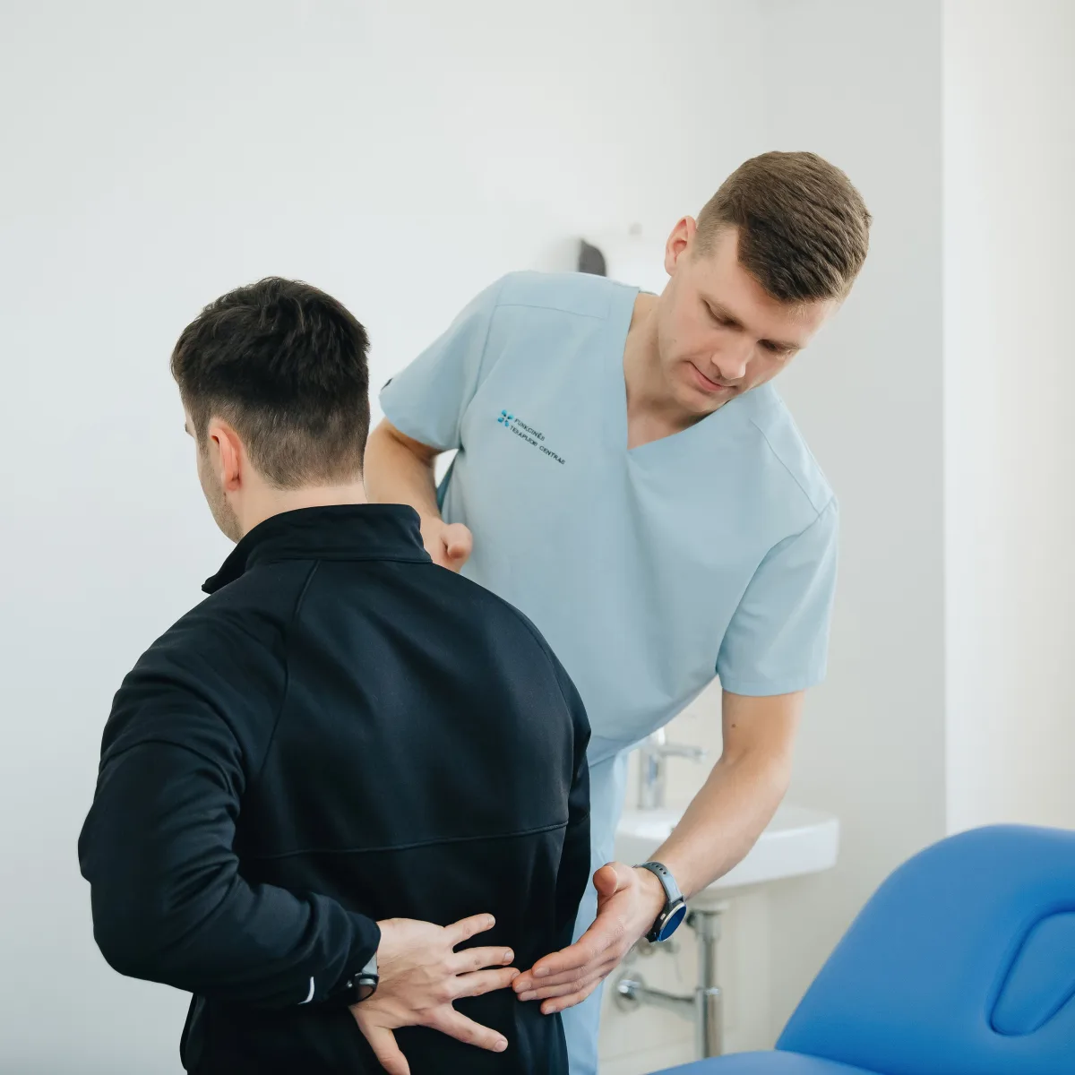 A physiotherapist examining the lower back of the person being treated.